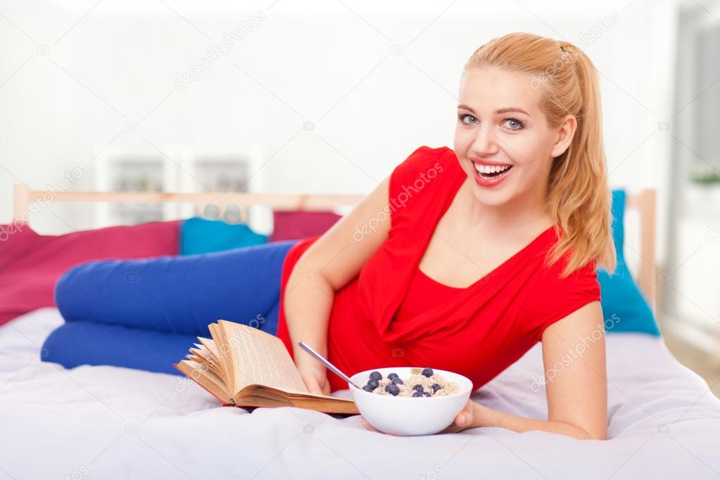 Young woman reading a book in bed