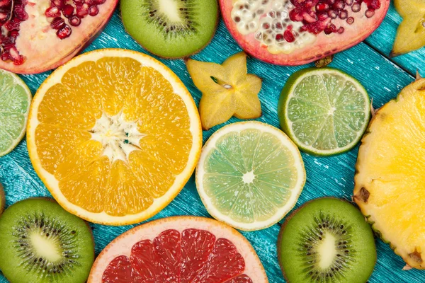 Colorful fruit slices on blue wood surface — Stock Photo, Image