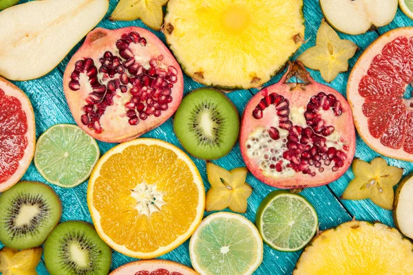 Colorful fruit slices on blue wood surface — Stock Photo, Image