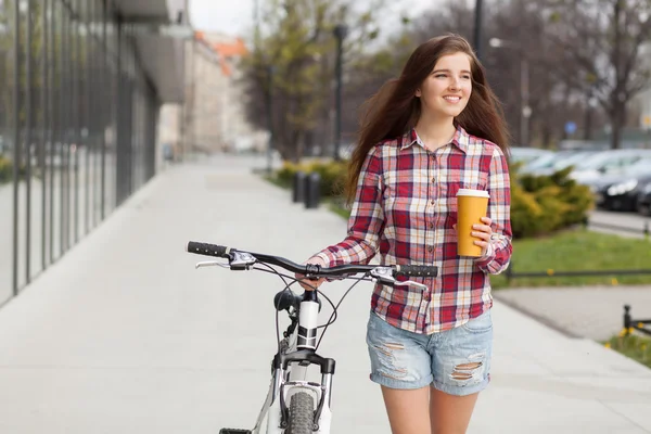 Jeune belle femme avec tasse de café et un vélo — Photo