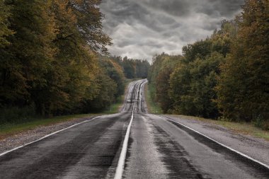 Bir fırtına gökyüzü altında karanlık asfalt yolu