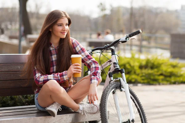 Ung kvinna dricker kaffe på en cykeltur — Stockfoto