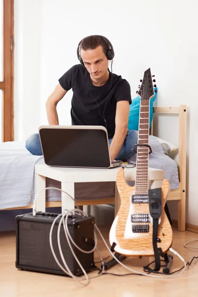 Mladý muž hraje na elektrickou kytaru doma — Stock fotografie