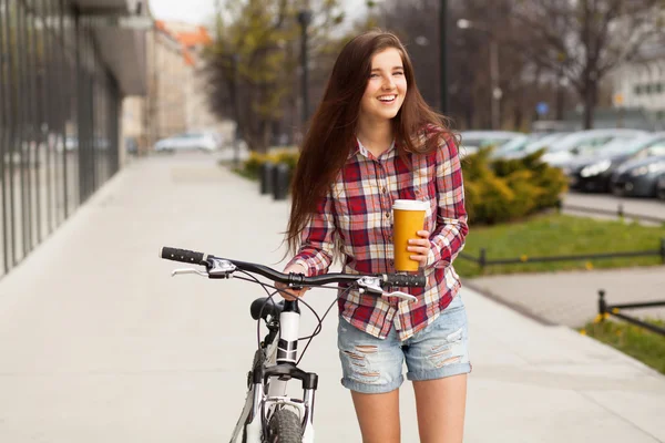 Young beautiful woman with coffee cup and a bicycle — Stock Photo, Image