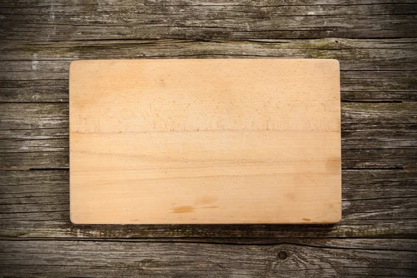 Cutting board on wooden background — Stock Photo, Image