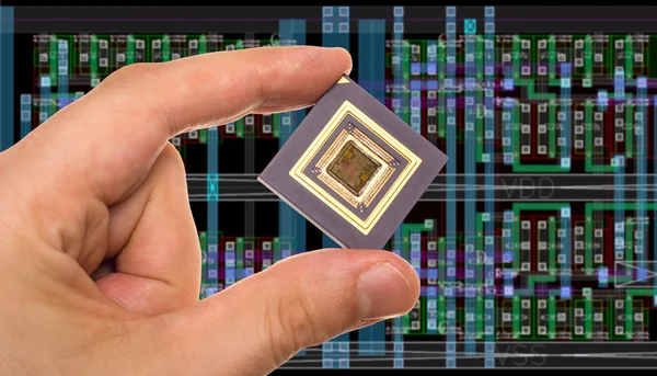 Microprocessor in hand in front of chip layout — Stock Photo, Image