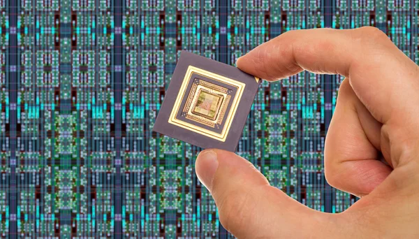 Microprocessor in hand in front of chip layout — Stock Photo, Image