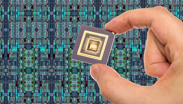 Microprocessor in hand in front of chip layout — Stock Photo, Image