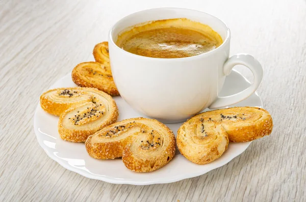 Puff cookies with poppy seeds, black coffee in white cup on plate on wooden table