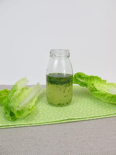 Vinaigrette en bouteille et feuilles de salade — Photo