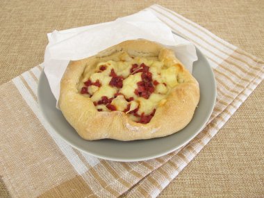 Peynirli ve yağsız kağıt torbada jambonlu pizza.