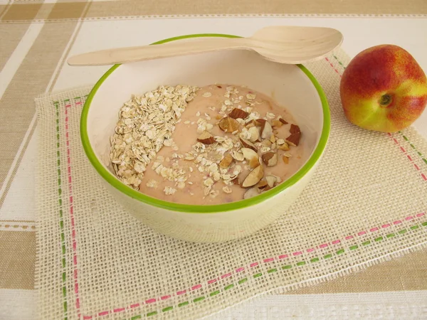 Smoothie bowl with rolled oats, nectarines and hazelnuts — Stock Photo, Image