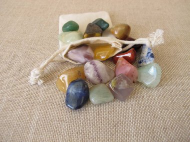 Tumbled colorful gemstones in a small bag clipart