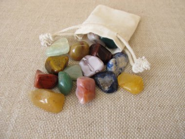 Tumbled colorful gemstones in a small bag clipart