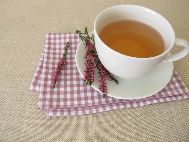 Calluna vulgaris 'ten bir fincan funda çayı ve çiçek filizleri.