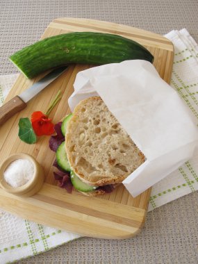 Cucumber sandwich in greaseproof paper bag for take away clipart
