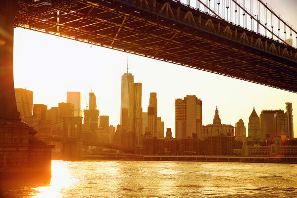 Lower Manhattan skyline under Manhattan Bridge at sunset, New York