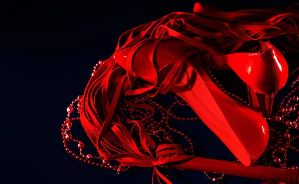 黑色背景上漂亮的专利皮革闪亮的女性红色高跟鞋 鞭子和珠子 — 图库照片