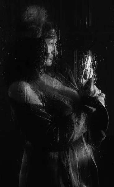 美丽的女人 手里拿着左轮手枪 躲在雨滴淋湿的玻璃杯后面 — 图库照片