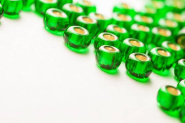 Beyaz arkaplanda dağınık yeşil küçük boncuklar