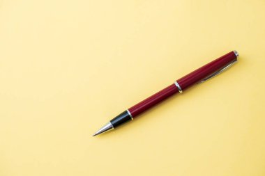 Güzel kırmızı tükenmez kalem sarı bir sırtüstü yatar