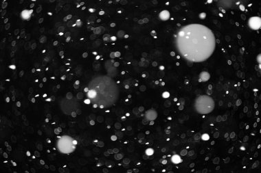 Gece gökyüzünün kara zemininde uçan ağır bir kardan güzel bir bokeh.