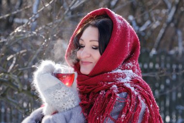 Kürklü ve başörtülü güzel yetişkin kadın şarapta çay içer.