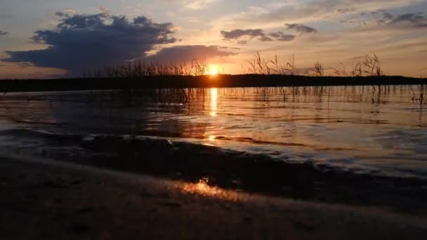 Egy tó partja és a naplemente az égen a felhők között — Stock videók