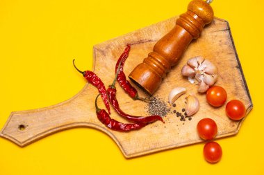 Kara biber, kırmızı biber ve sarımsak, sarı bir grupta tahta kesme tahtasında.