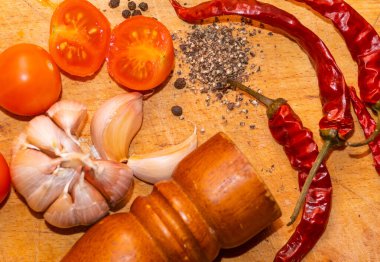 Karabiber, kırmızı biber, sarımsak ve kiraz domatesleri kesme tahtasında.