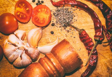 Karabiber, kırmızı biber, sarımsak ve kiraz domatesleri kesme tahtasında.