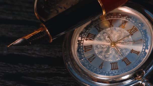 Reloj de bolsillo y pluma estilográfica de cerca en una mesa de madera negro — Vídeos de Stock