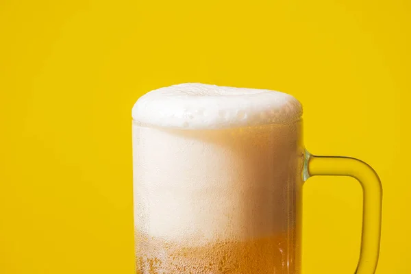 黄色の背景に冷たい泡のビールと完全なマグカップ — ストック写真