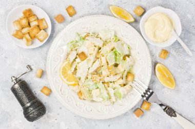 Tavuklu Sezar salatası, marul, parmesan peyniri, kızarmış ekmek ve mayonez sosu gri beton arka planda.