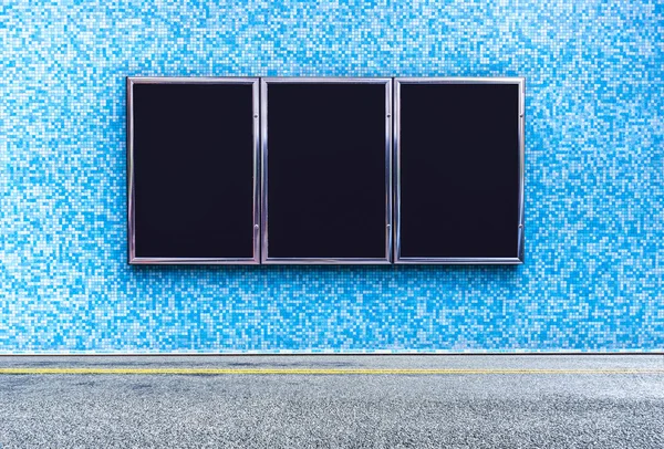 Asphaltstraße nahe blauer Mauer mit schwarzen Werbetafeln — Stockfoto