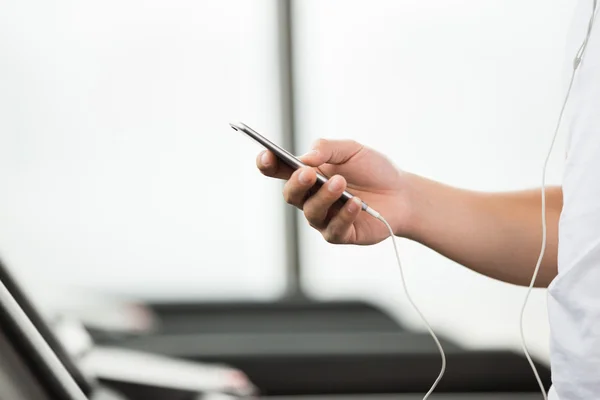 Asiático hombre usando smartphone en moderno gimnasio — Foto de Stock