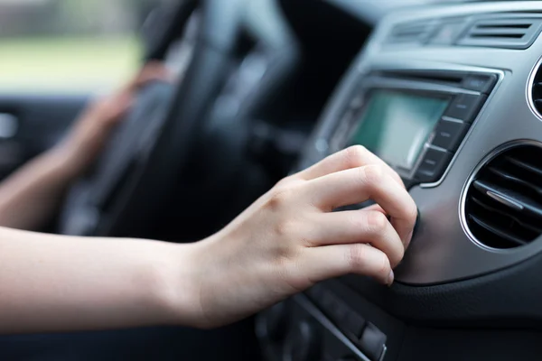 Woman turning button of radio in car — Stock Photo, Image