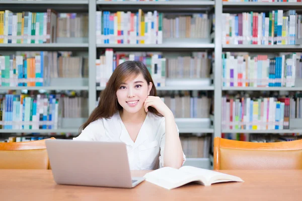 Menina asiática com laptop na biblioteca da escola — Fotografia de Stock