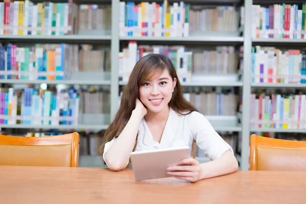 Азиатская девушка с планшетом в школьной библиотеке — стоковое фото