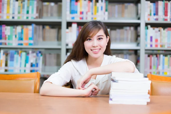 Asiatisk jente med bøker på skolebiblioteket – stockfoto