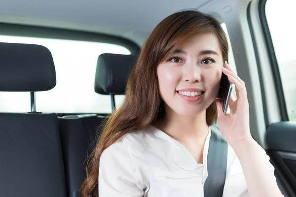 Junge asiatische Mädchen mit Telefon im Auto — Stockfoto