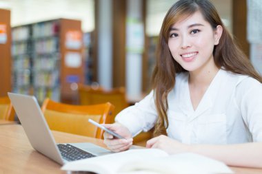 kız öğrenci dizüstü bilgisayar ve telefon Kitaplığı'nda