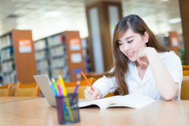 Kız üniversite öğrencisi Kütüphane içinde laptop ile