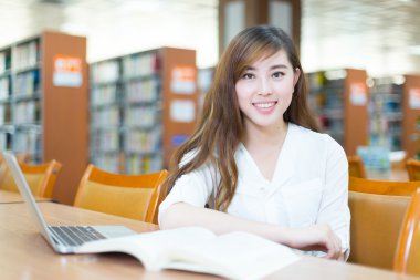 Kız üniversite öğrencisi Kütüphane içinde laptop ile