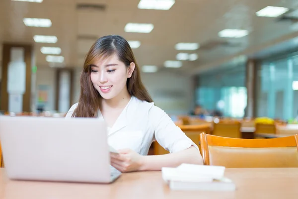 Estudante universitário menina com laptop na biblioteca — Fotografia de Stock