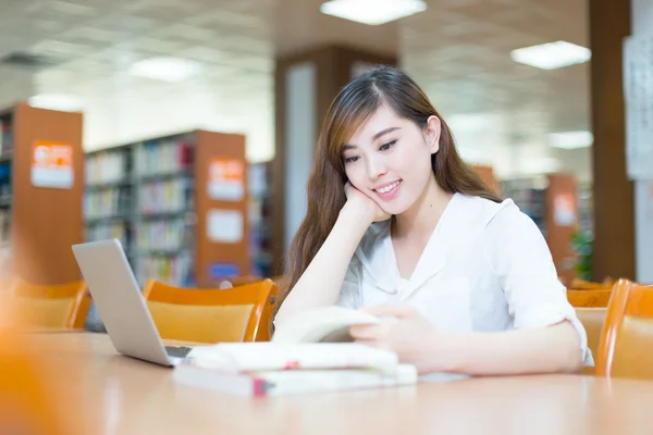 Estudante universitário menina com laptop na biblioteca — Fotografia de Stock