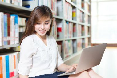 Kız üniversite öğrencisi Kütüphane içinde laptop ile