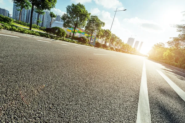 Empty asphalt road in modern city at sunrise — Stock Photo, Image