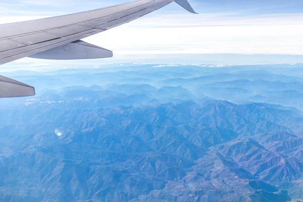 Landschap van bergen door raam van vliegtuig — Stockfoto