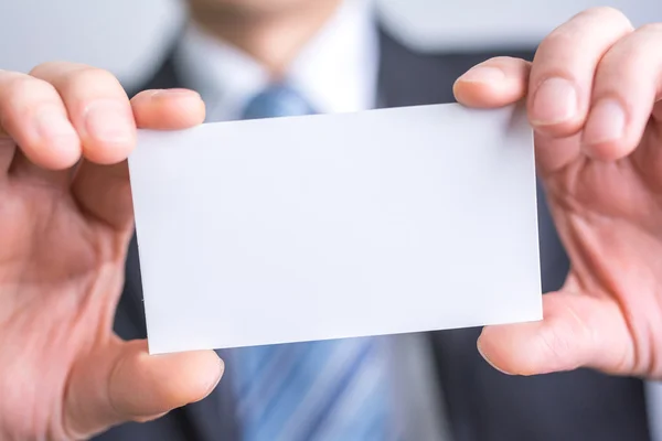 Бизнесмен, держащий в руках белую бланковую бумагу — стоковое фото